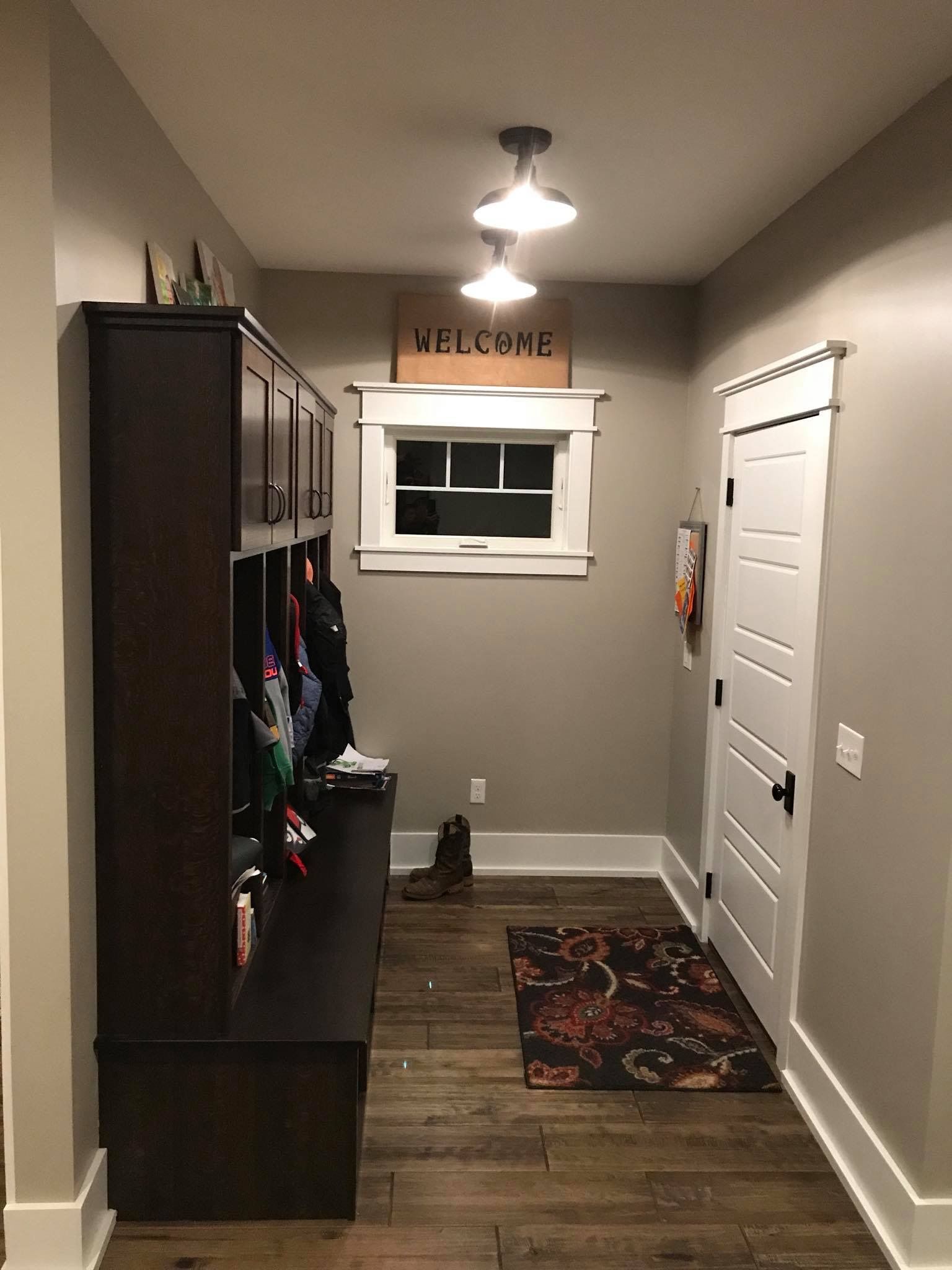Narrow hallway with dark wood cabinet, white door, window, and patterned runner rug.