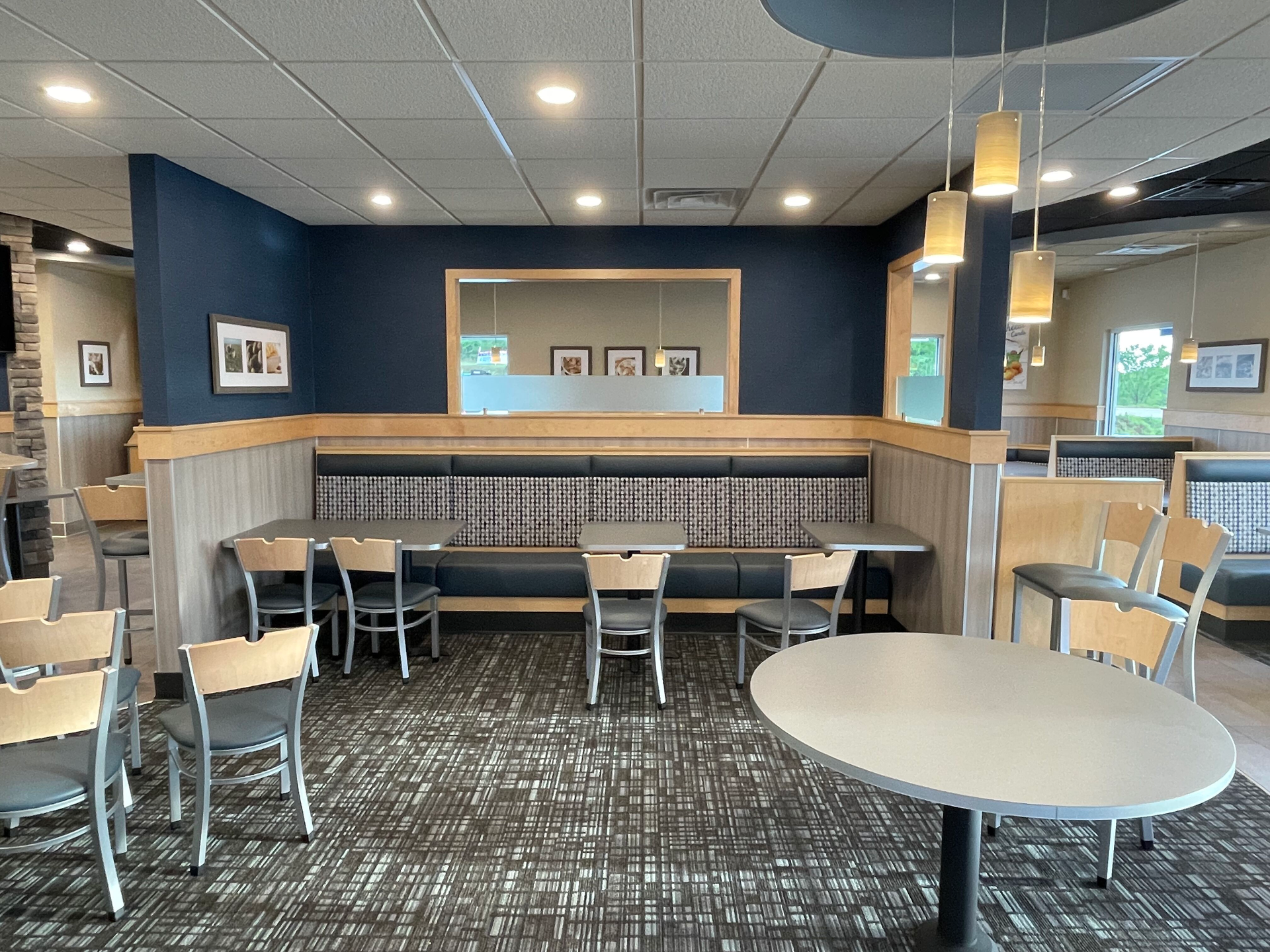 Empty modern cafe seating area with gray chairs, round tables, and blue walls