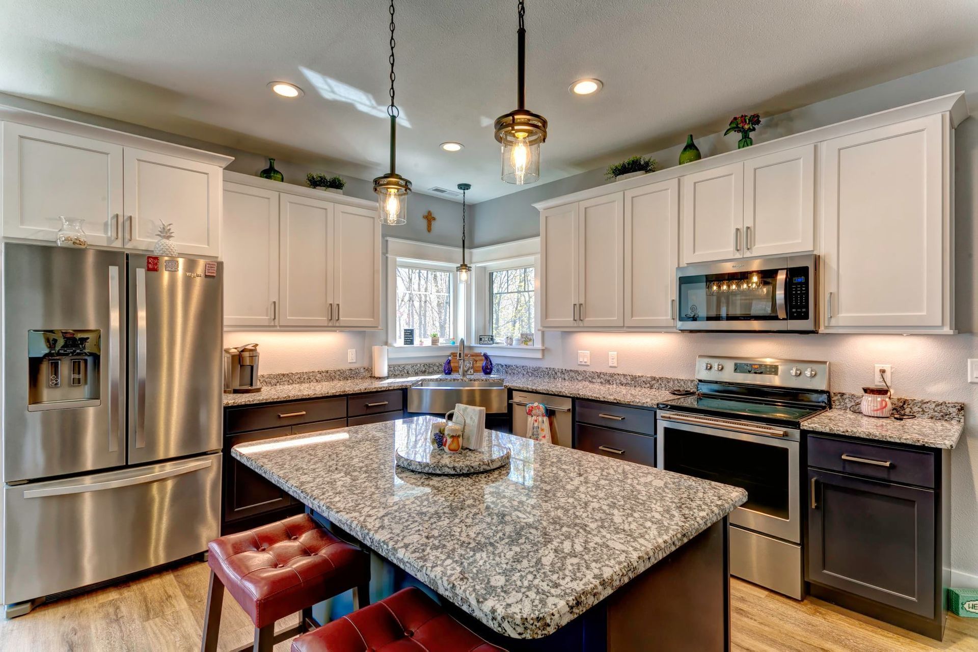 Modern kitchen with white cabinets, stainless steel appliances, granite island, and pendant lighting