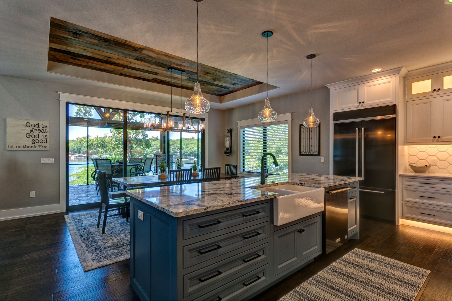 Modern kitchen with dark island, pendant lights, wood beams, and large sliding doors to a patio