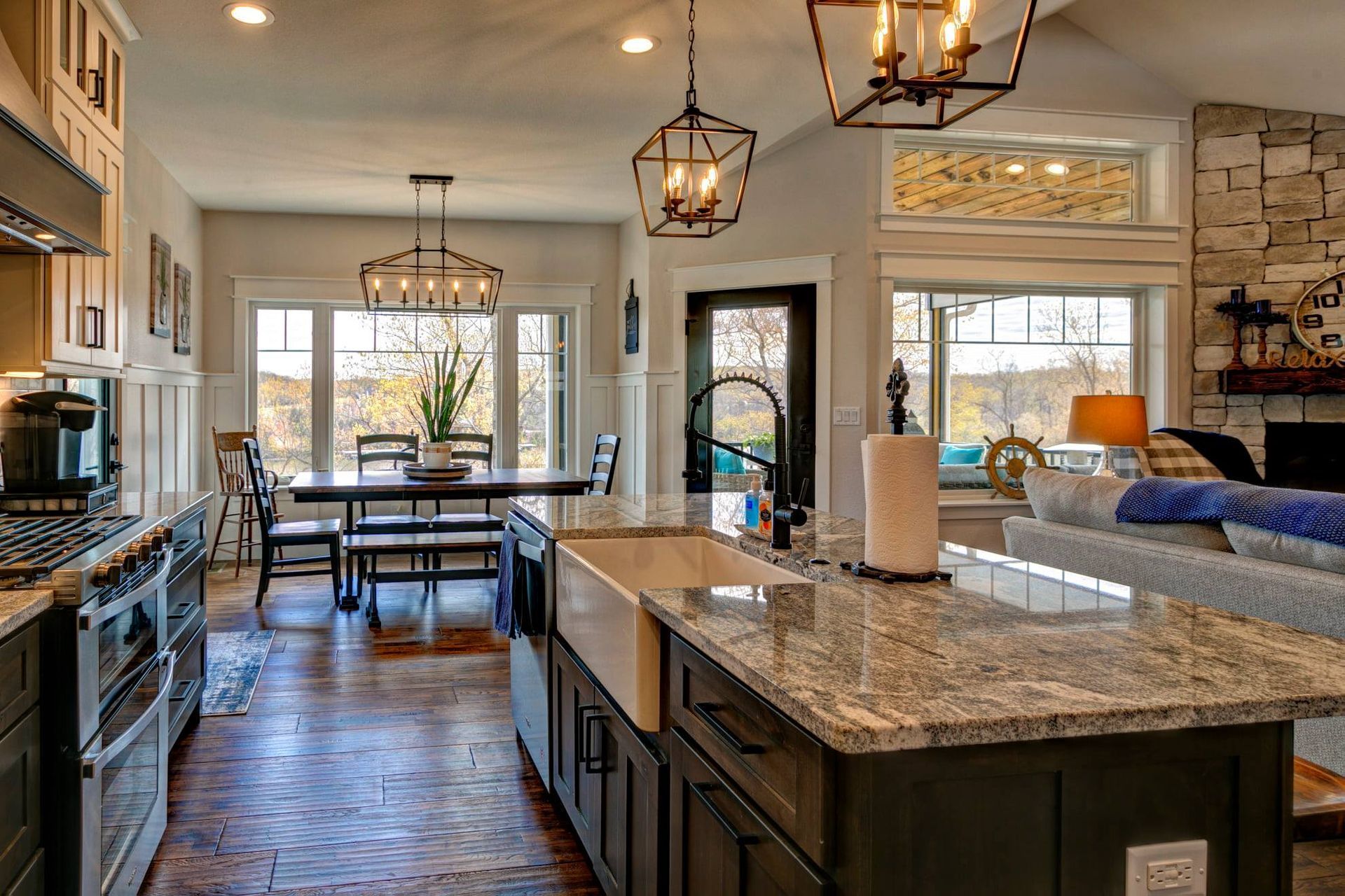 Modern open-concept kitchen and dining area with granite island, pendant lights, and large windows