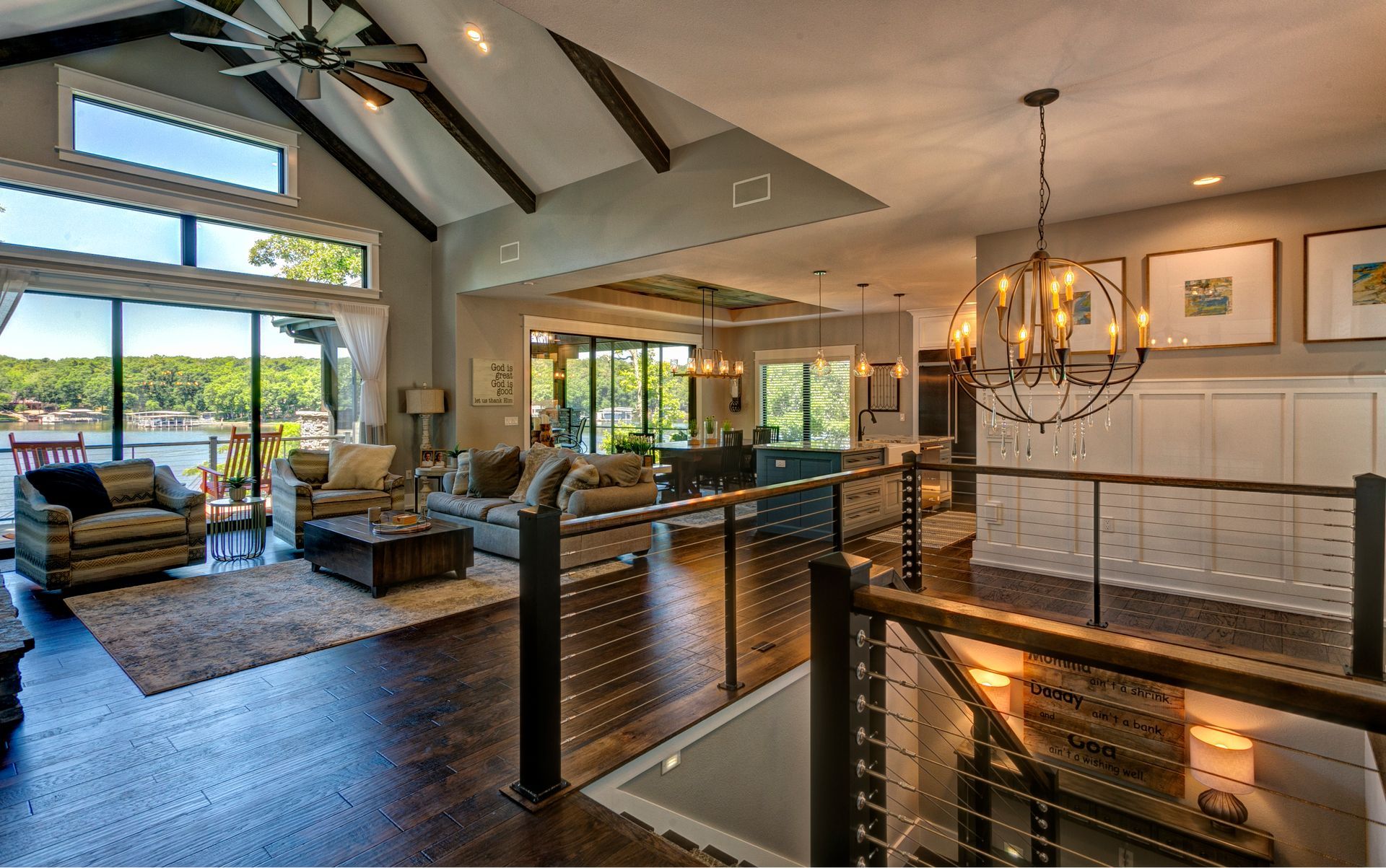 Bright open-concept living room with vaulted ceiling, stone fireplace, and large windows overlooking water