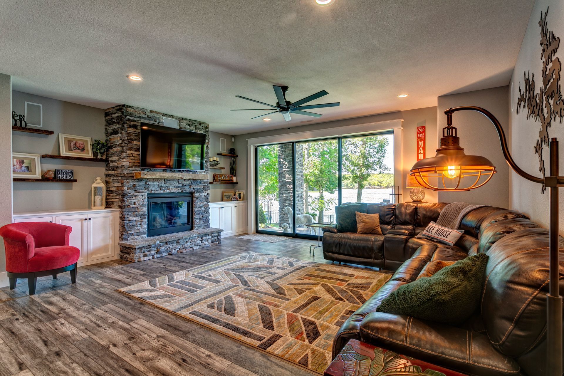 Spacious living room with stone fireplace, large sectional sofa, patterned rug, and sliding glass doors to outside