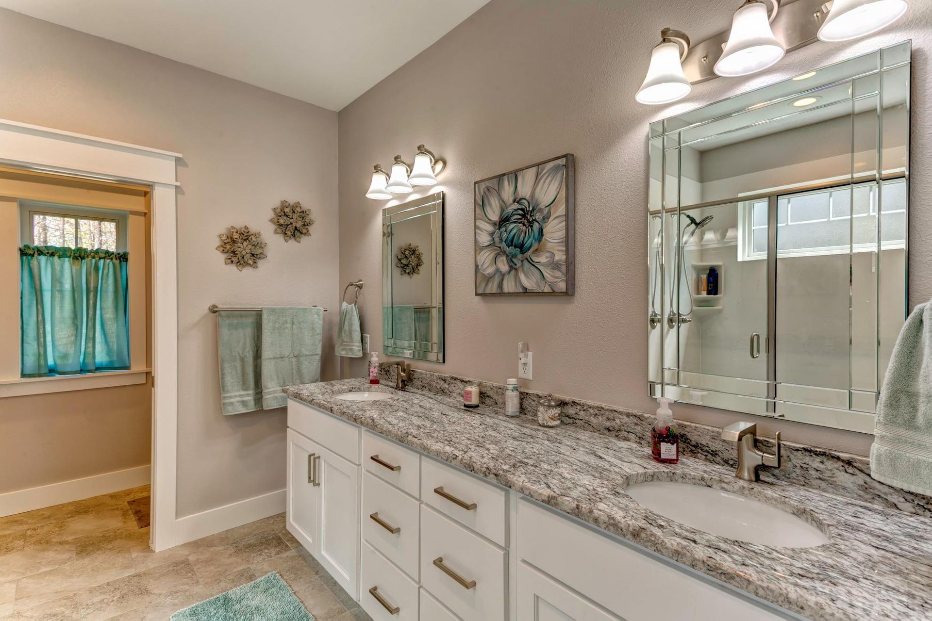 Modern bathroom with double vanity, large mirrors, granite countertop, and wall sconces