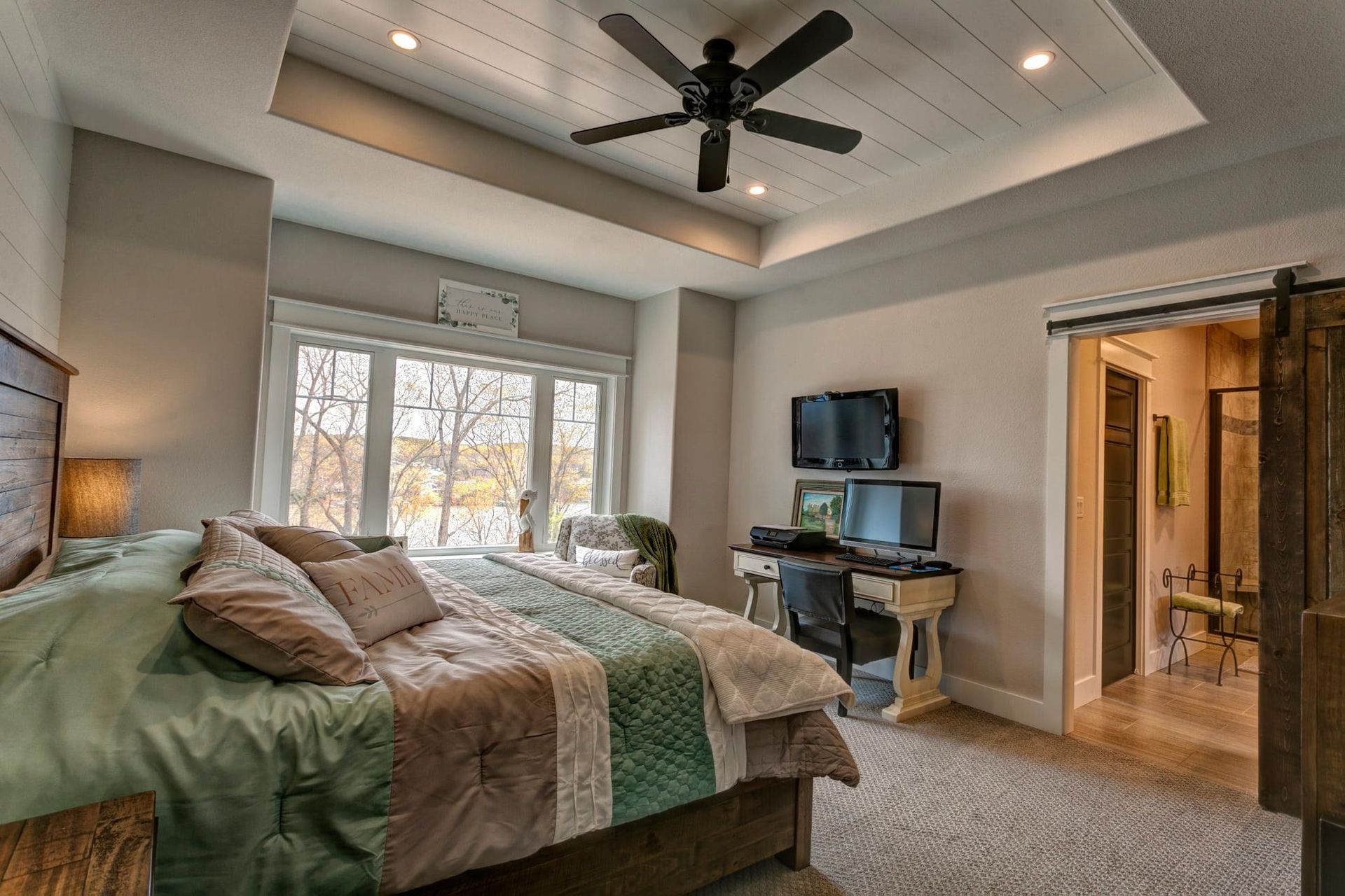 Bedroom with bed, large window, ceiling fan, and desk in a modern home