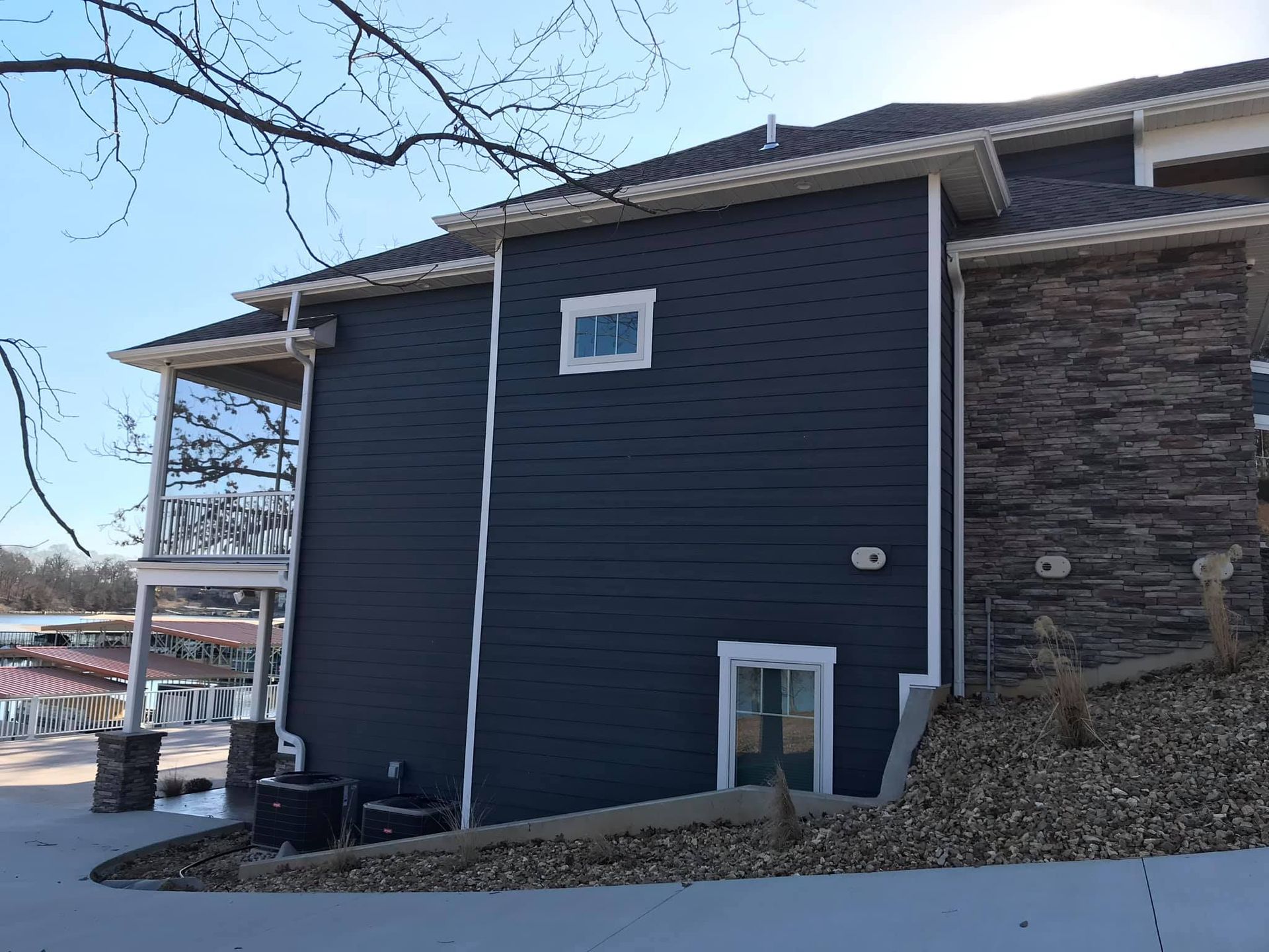 Exterior of a dark blue house with stone siding and snow on the ground, viewed from the side