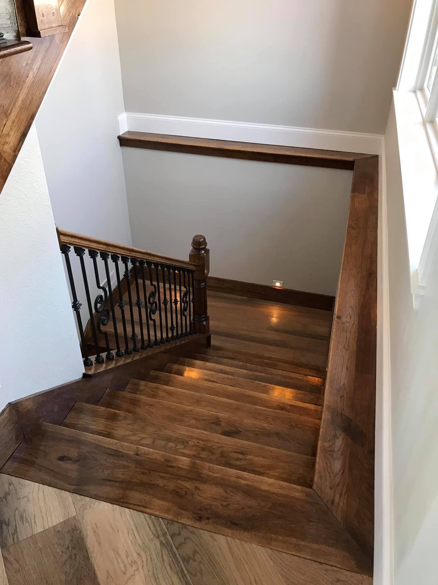 Wooden staircase with dark railing descending to a lower landing in a home interior