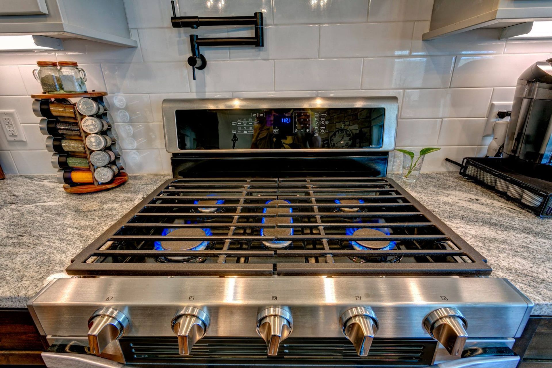 Stainless steel gas stove with blue flames in a modern kitchen