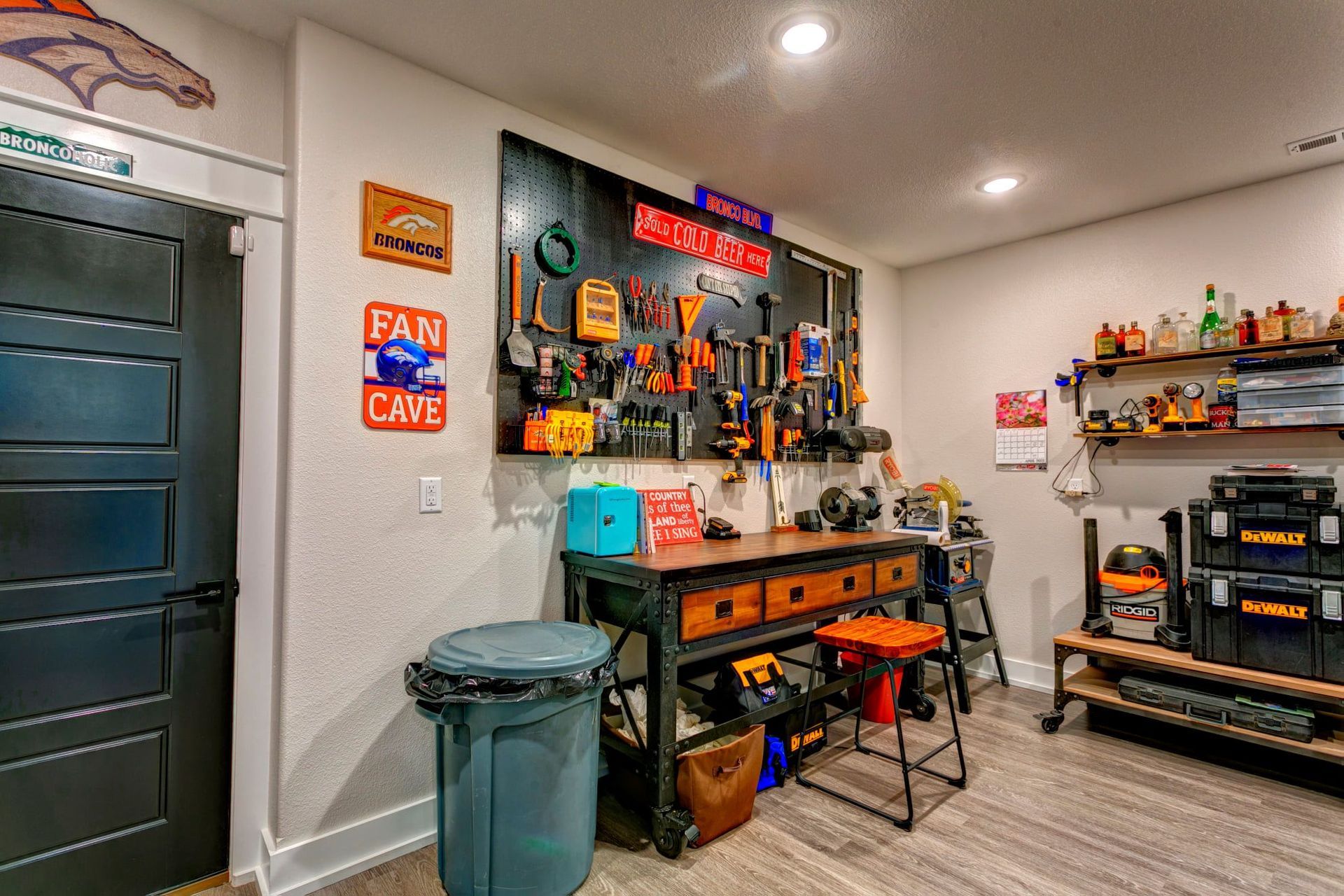 Garage workshop with tools, shelves, and an orange workbench next to a trash can.