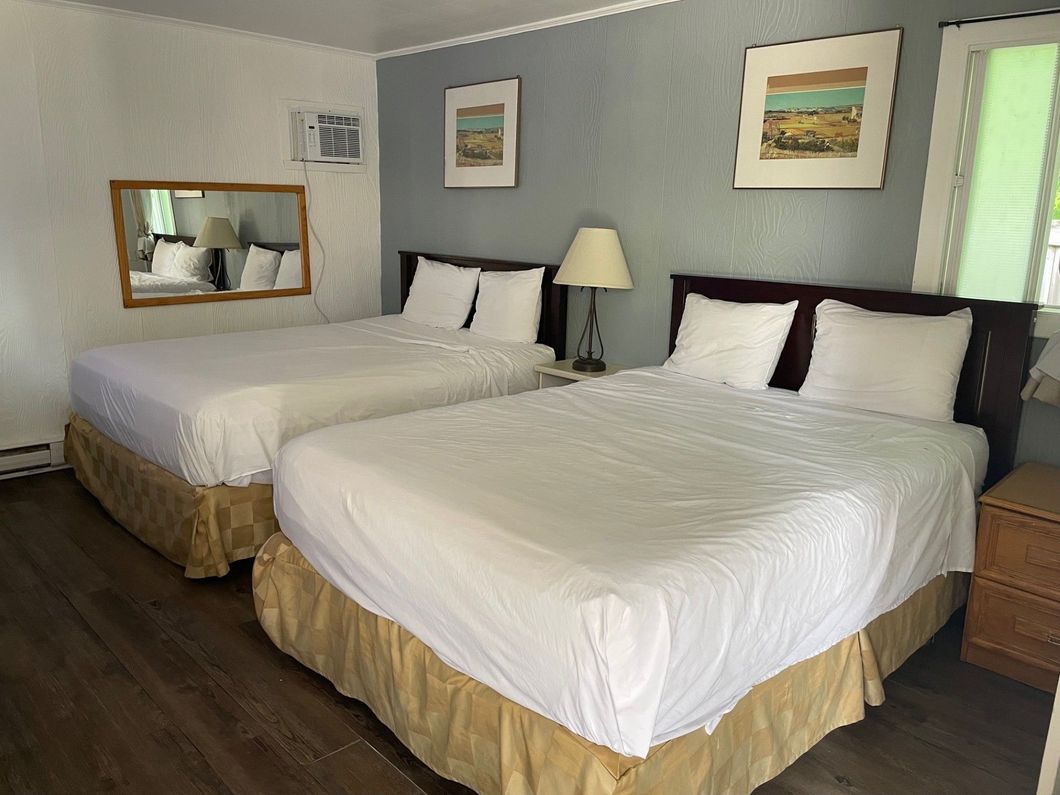 Une chambre d'hôtel avec deux lits et un miroir sur le mur.