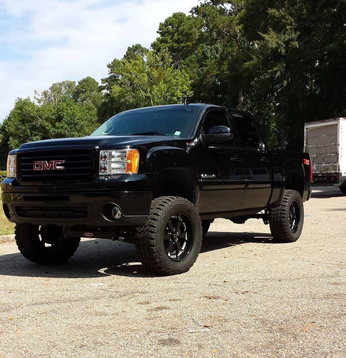 A black gmc truck is parked in a gravel lot