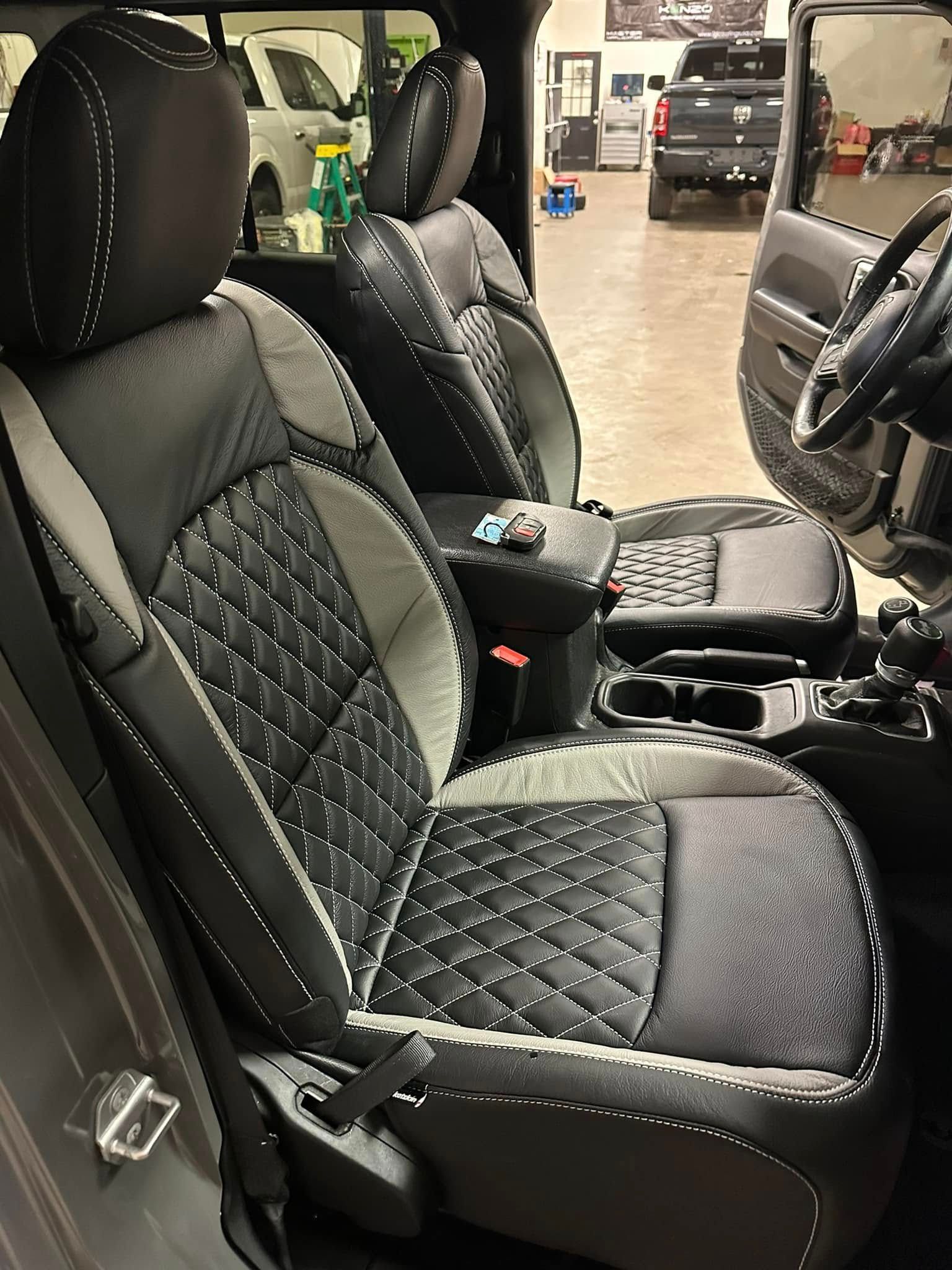The interior of a jeep wrangler with black and grey seats and a steering wheel.