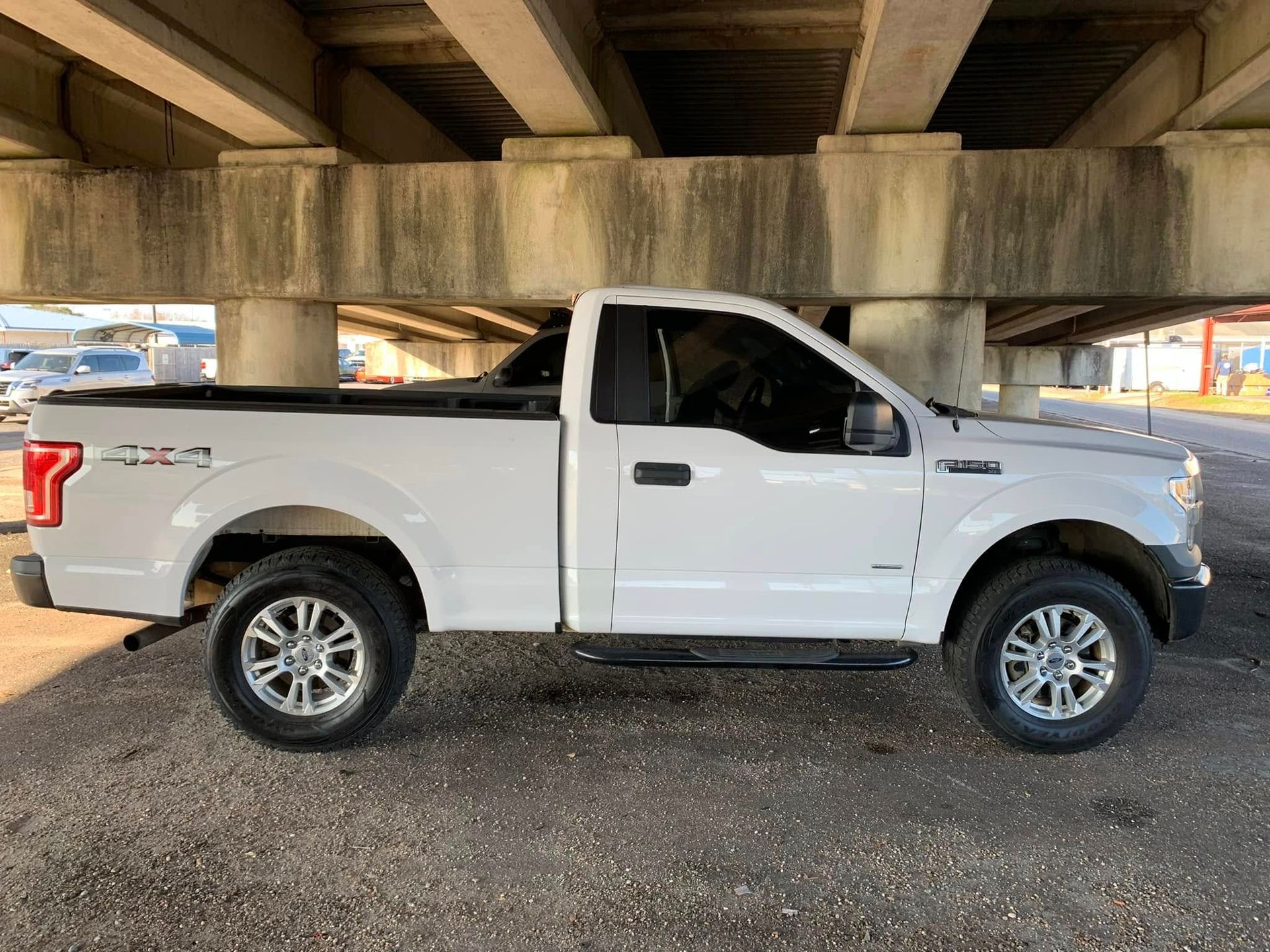A white pickup truck is parked under a bridge.