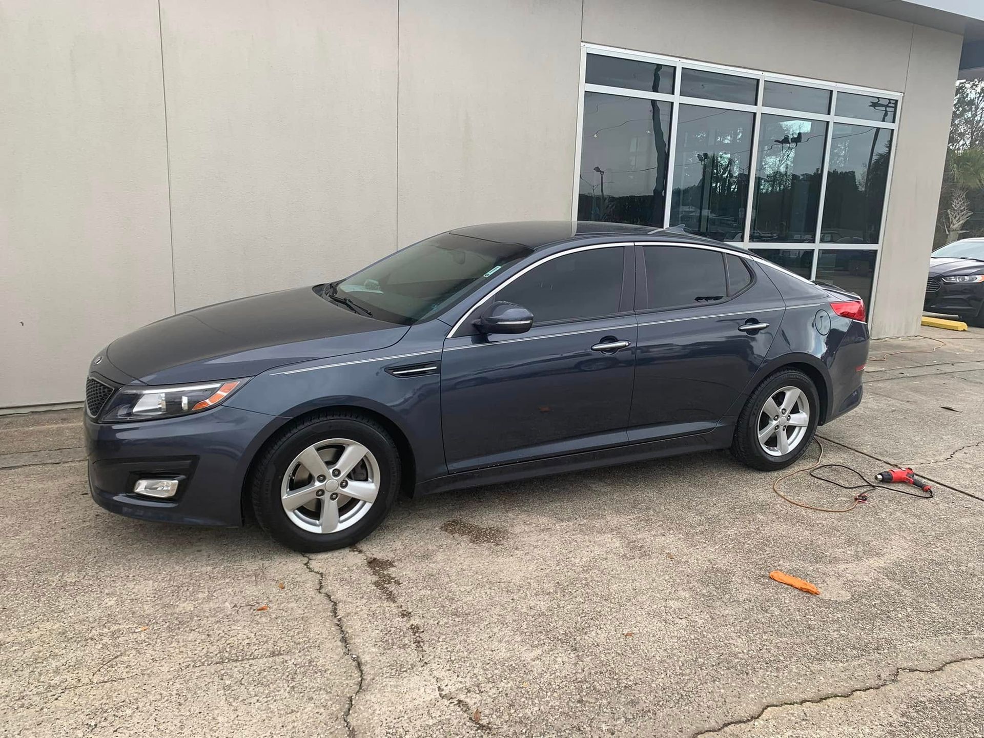A gray car is parked in front of a building.
