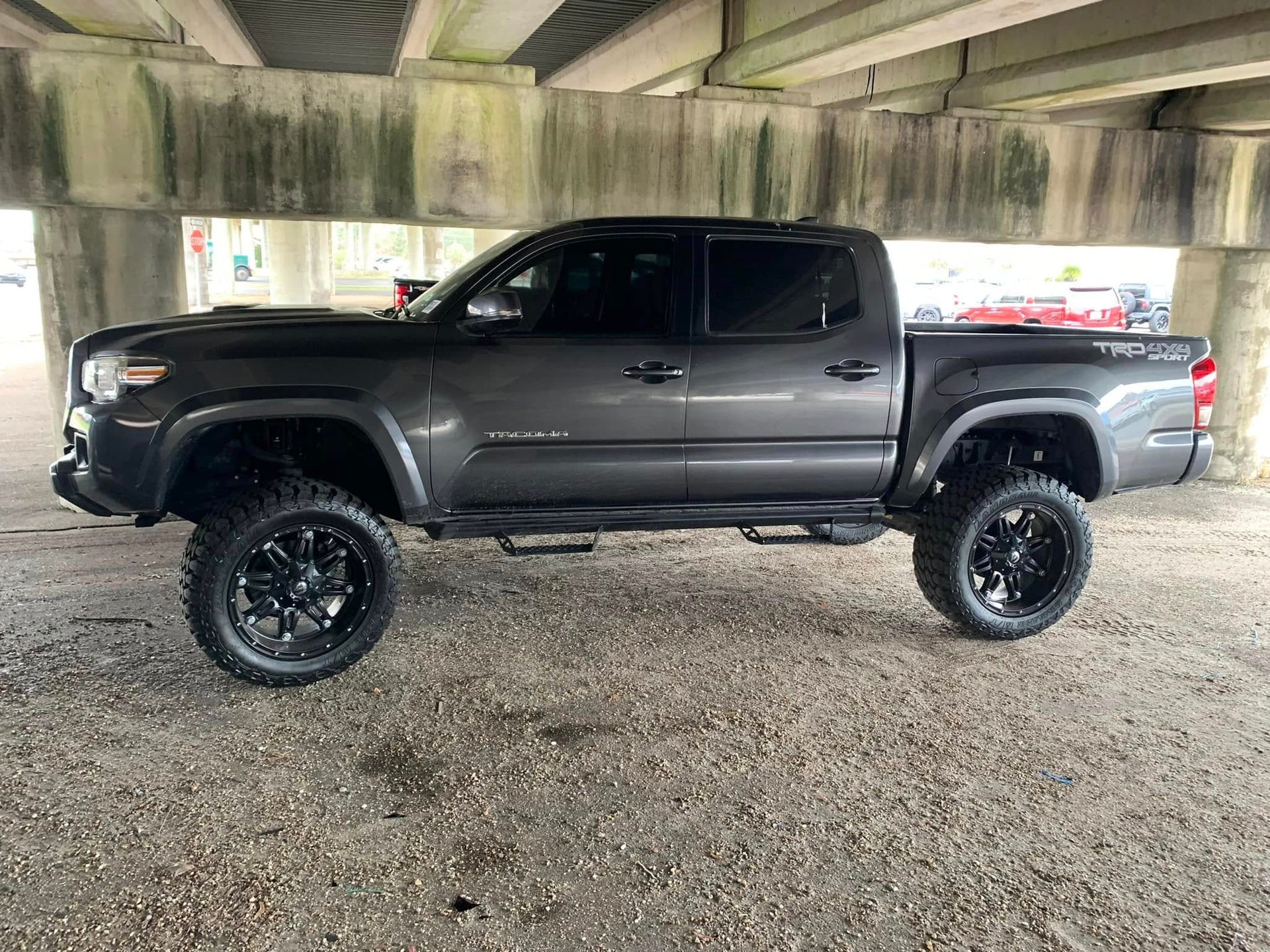 A toyota tacoma truck is parked under a bridge.