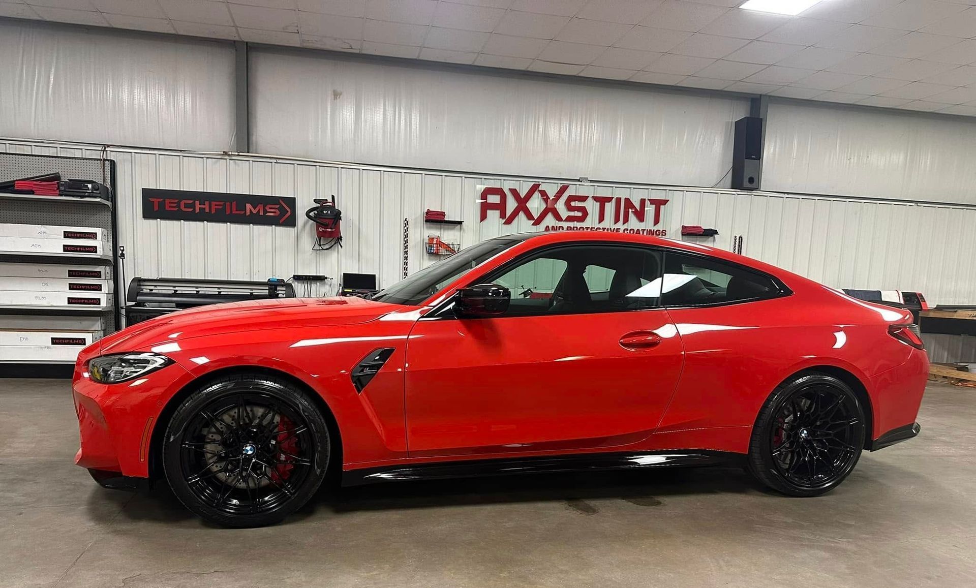 A red bmw m4 coupe is parked in a garage.
