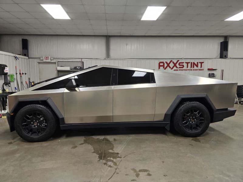 A silver tesla cybertruck is parked in a garage.