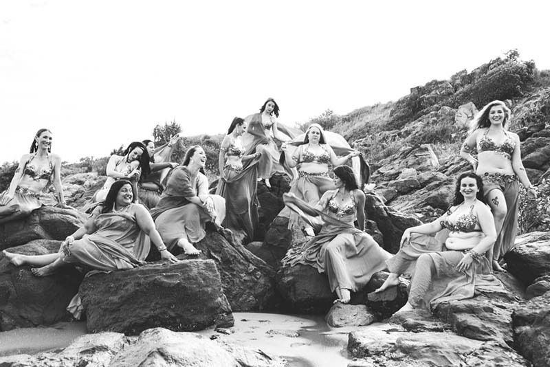 A Group Of Women Are Sitting On Rocks On A Beach — Global Dance Collective In West End, QLD