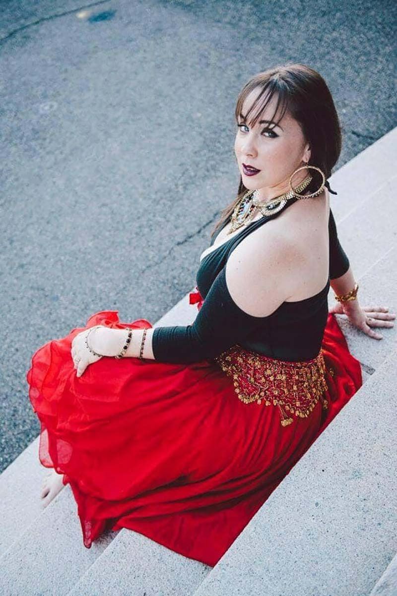 A Woman In A Red Skirt And Black Top Is Sitting On A Set Of Stairs — Global Dance Collective In West End, QLD