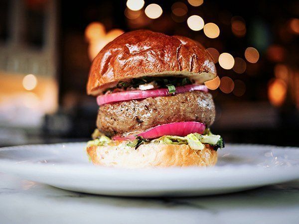 A close up of a hamburger on a white plate.