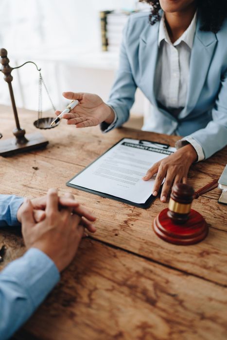 Lawyer discussing a contract at a wooden desk with a gavel and scales of justice
