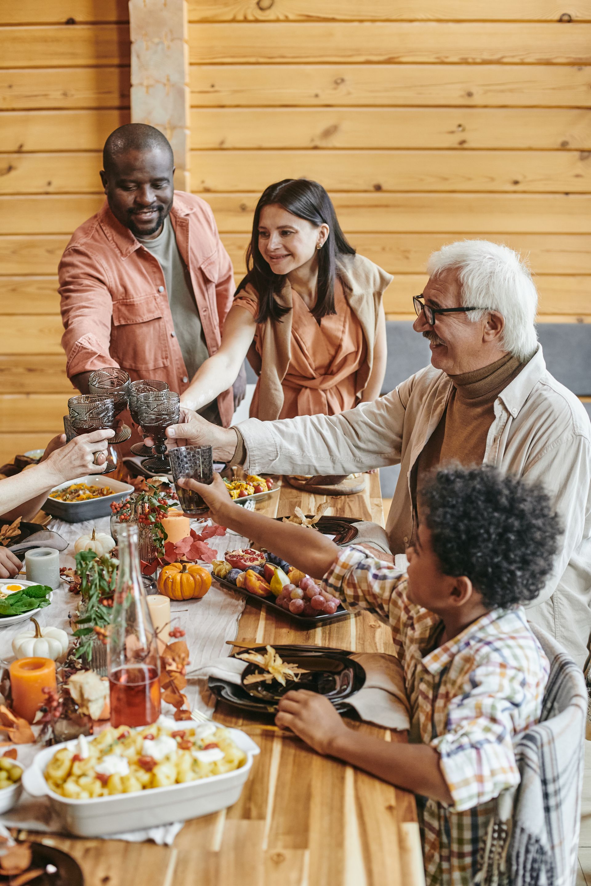 Friends sharing a meal and drinks at a long wooden table in a bright, casual dining space
