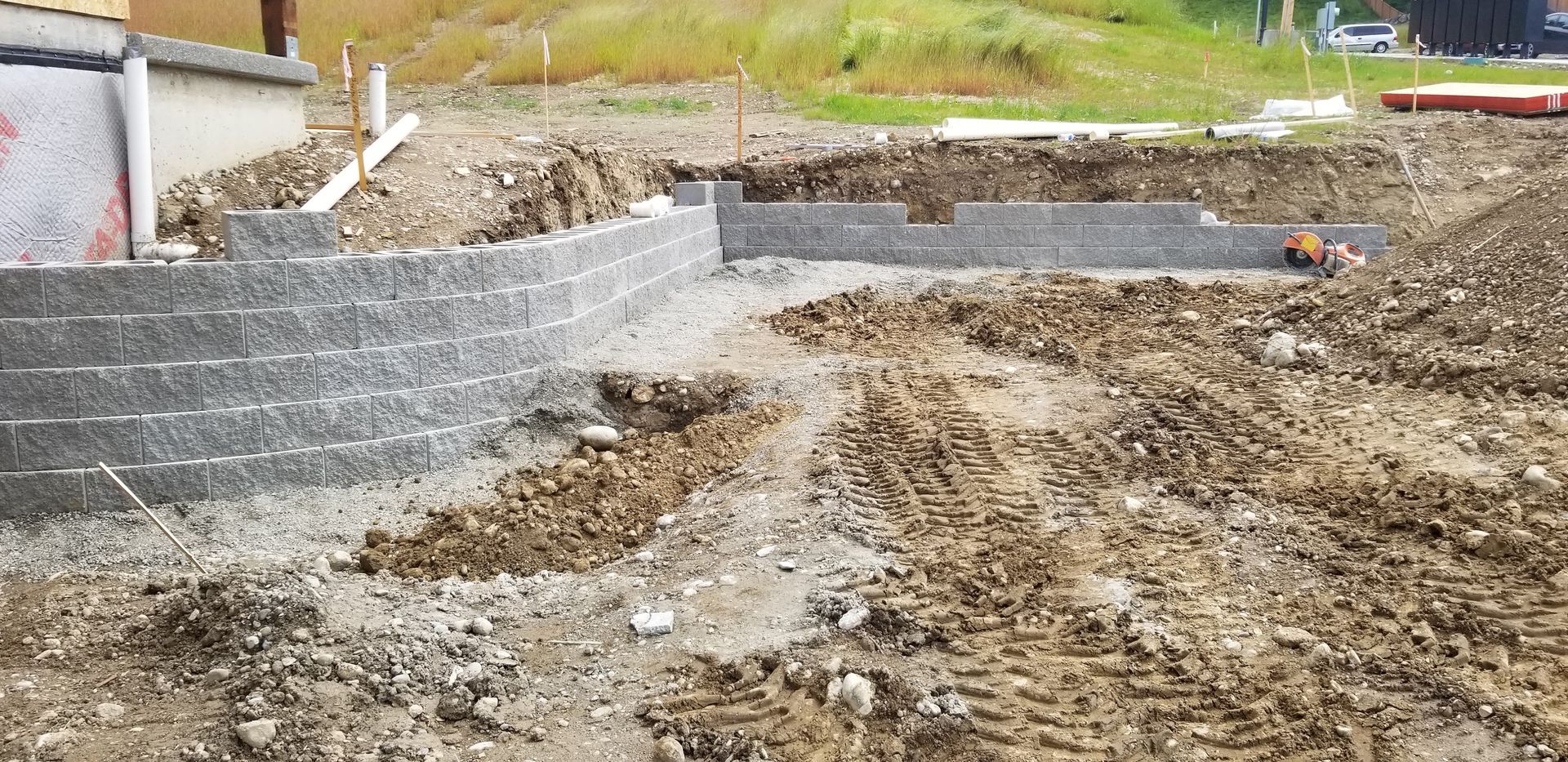 Construction site with tiered retaining wall and excavated foundation.
