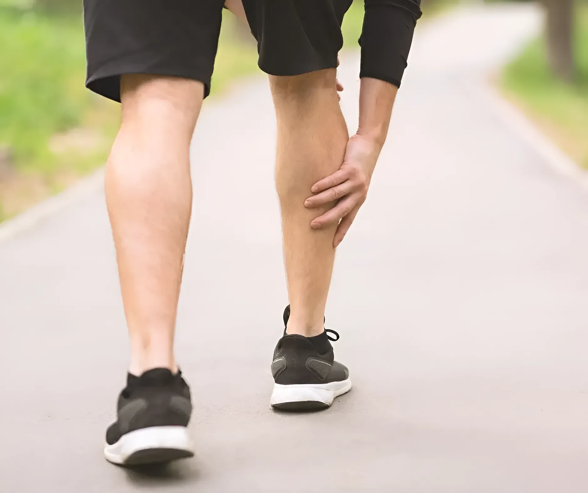 Runner Holding His Calf in Pain on a Paved Path — Barolin Physiotherapy Services in Bundaberg South, QLD