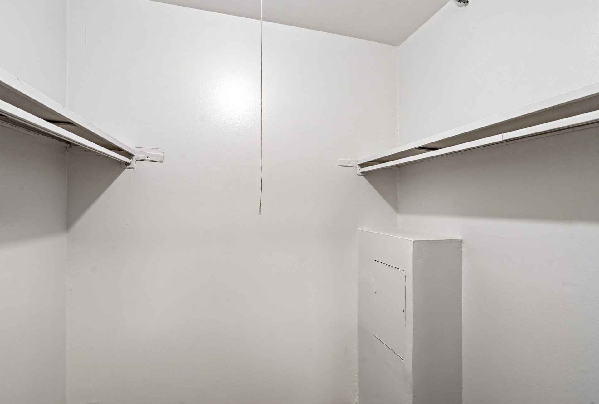 White walk-in closet with two parallel clothing rods and shelves.