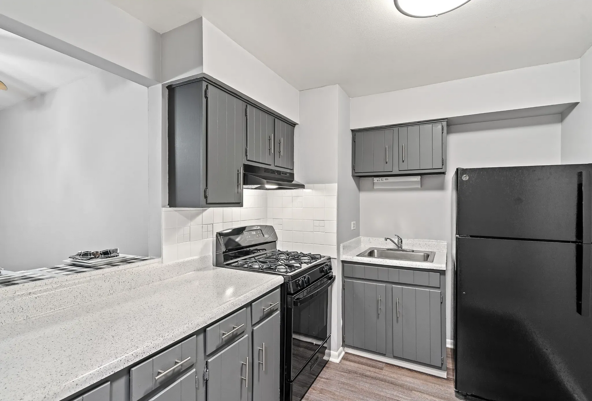 Gray kitchen with black appliances, white countertops and cabinets.