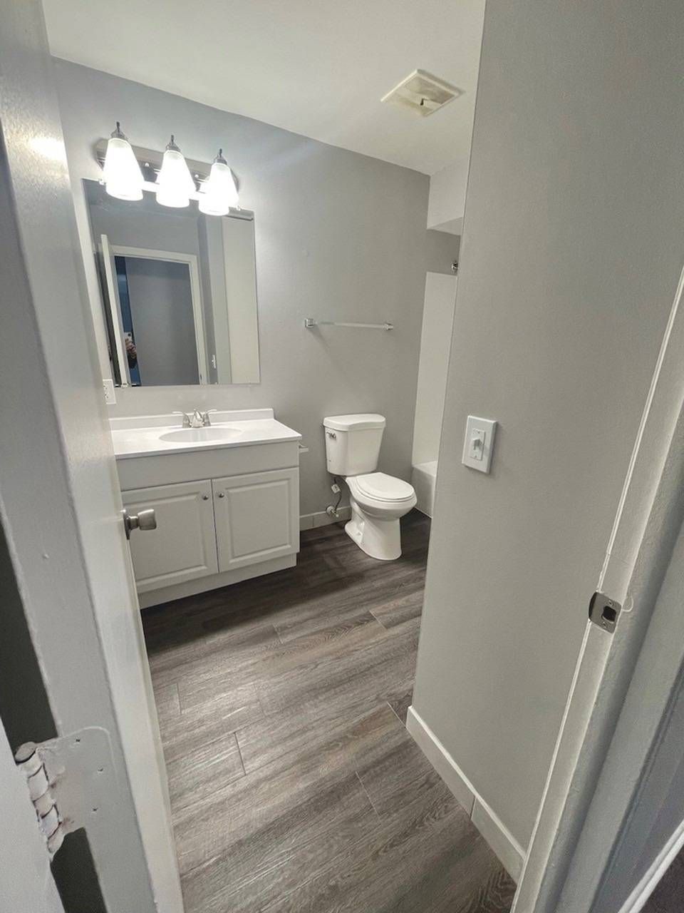 Bathroom with white vanity, mirror, toilet, and tub/shower.