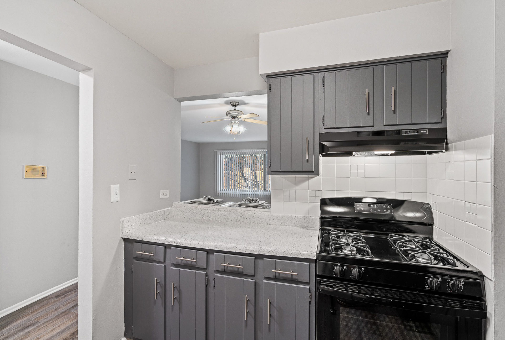 Kitchen with gray cabinets, white tile backsplash, and a black gas range.