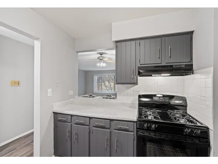 Gray kitchen with dark cabinets, white countertops, and black stove.