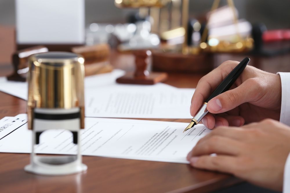 Person Writing on a Document at a Desk — Money Spider Conveyancing In Katherine, NT
