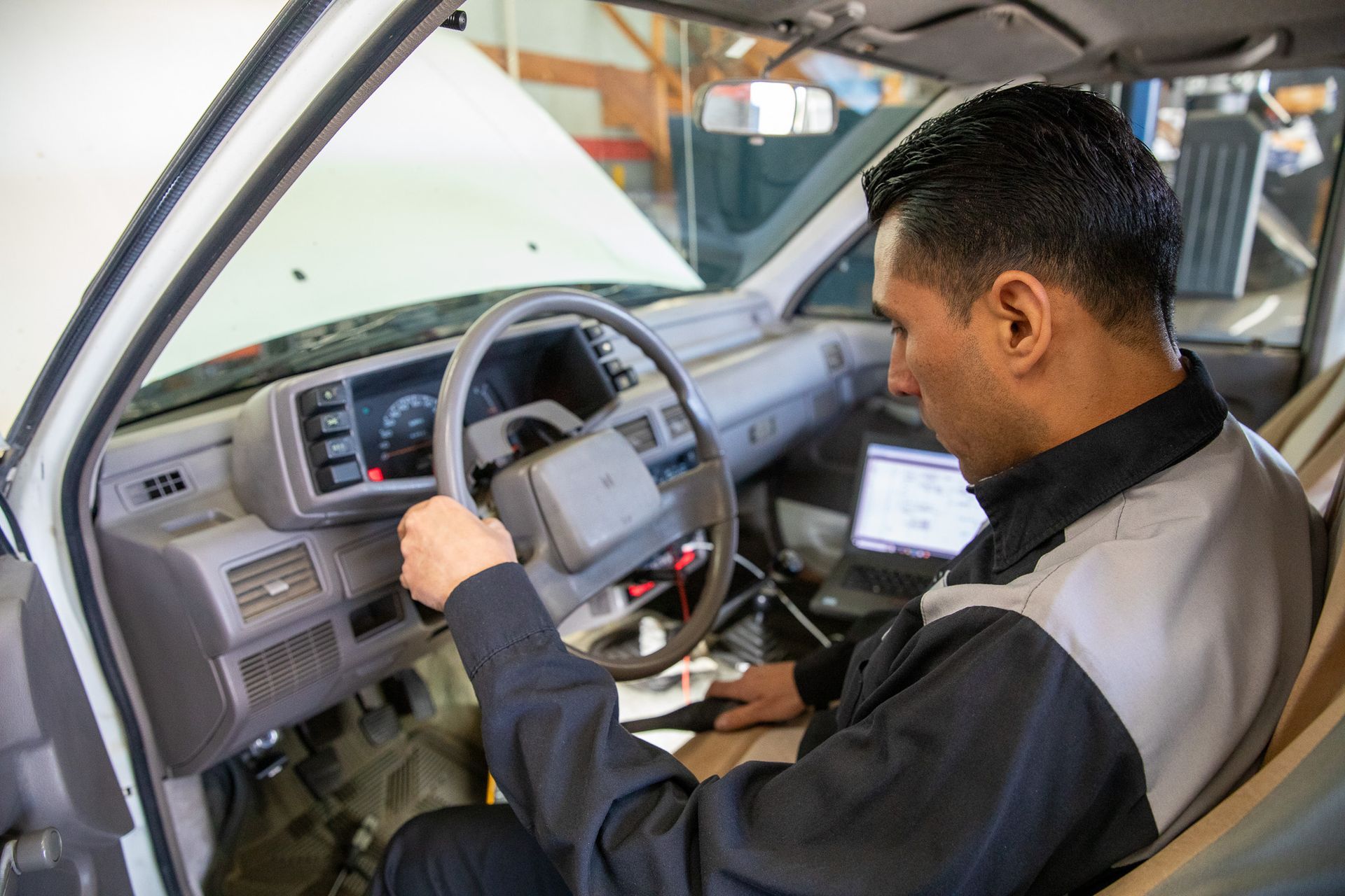 Mechanic inspecting a car dashboard and steering wheel with the driver door open