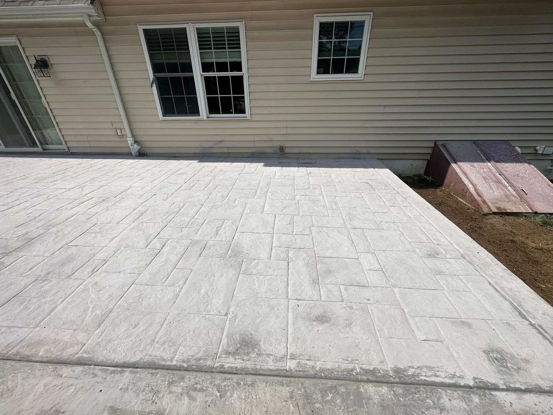 White flat roof beside beige house siding with windows and a small grassy yard edge