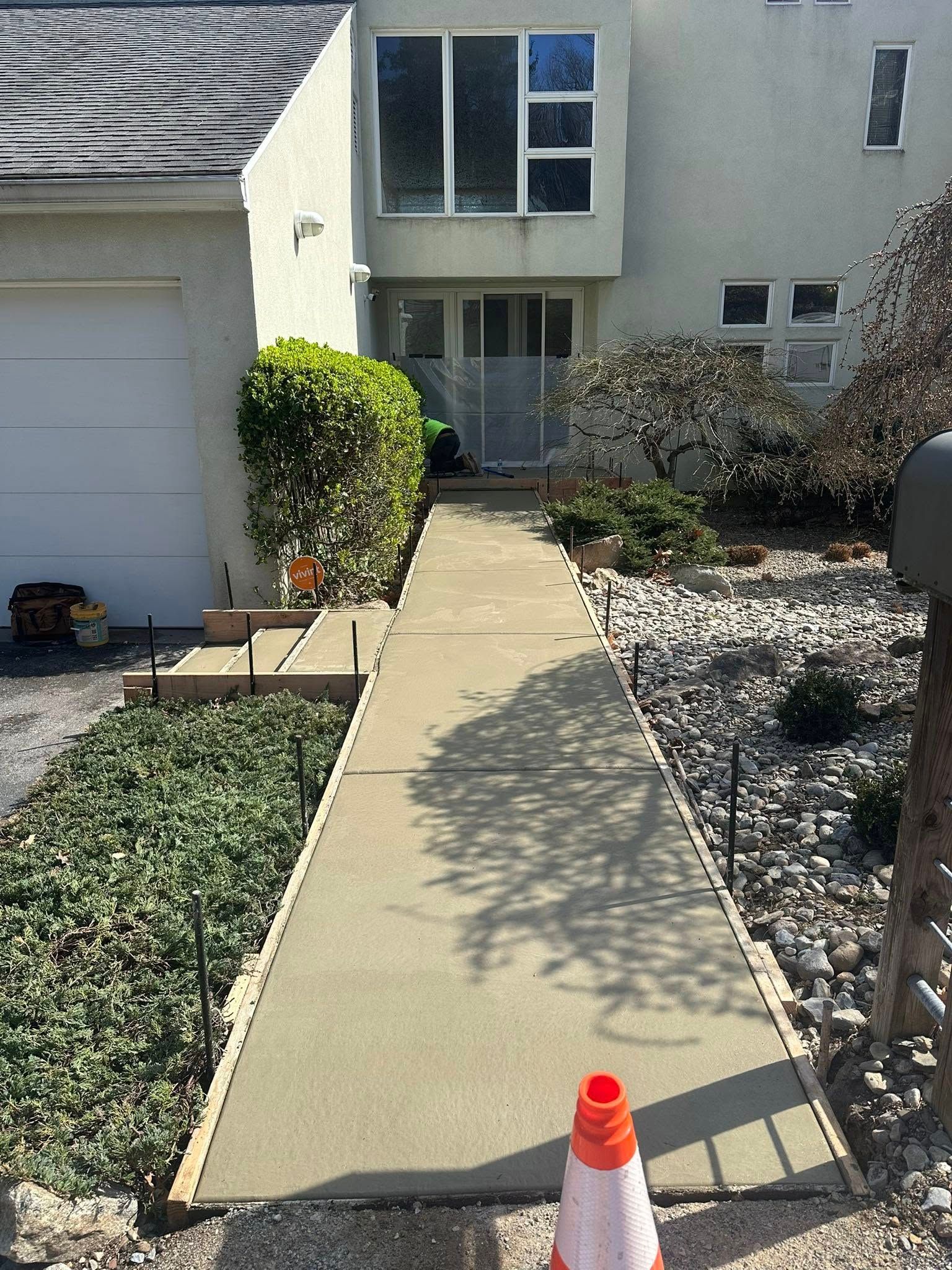 Front walkway to a house with a traffic cone at the entrance and landscaping on both sides