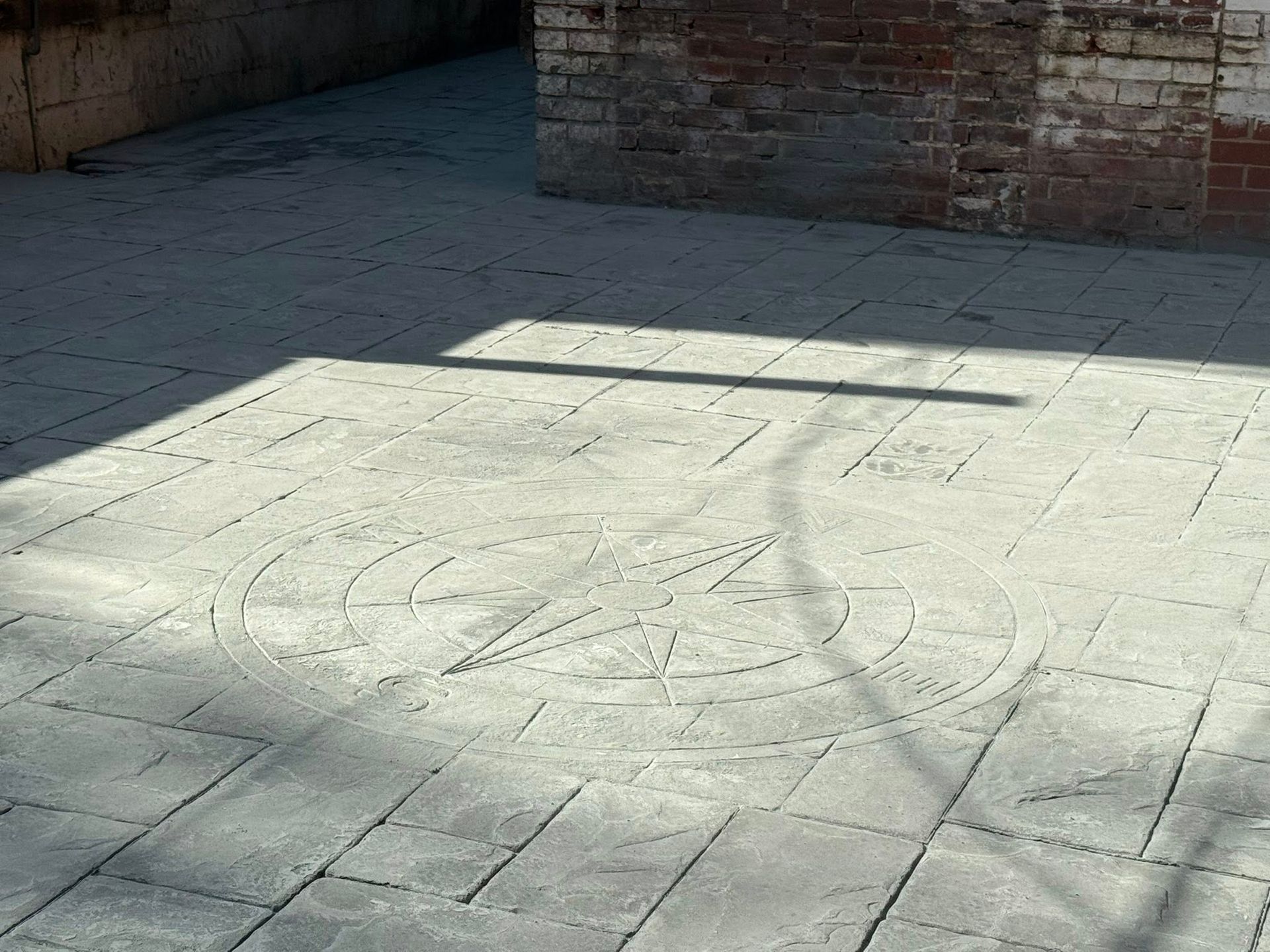 Sunlit stone courtyard with a chalk drawing on the ground near a brick wall