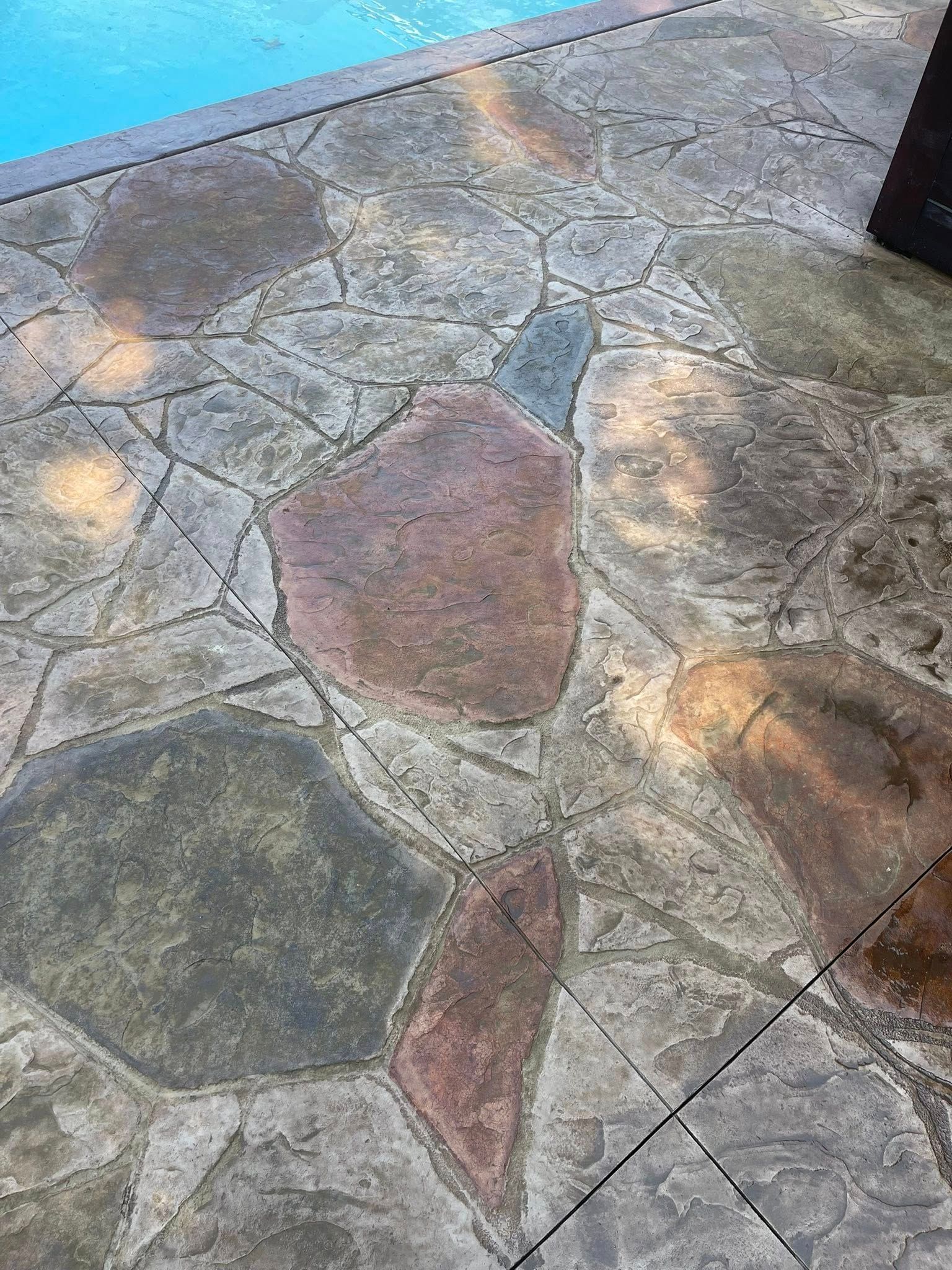 Stone-paved outdoor patio with irregular gray and reddish slabs and sunlight patches
