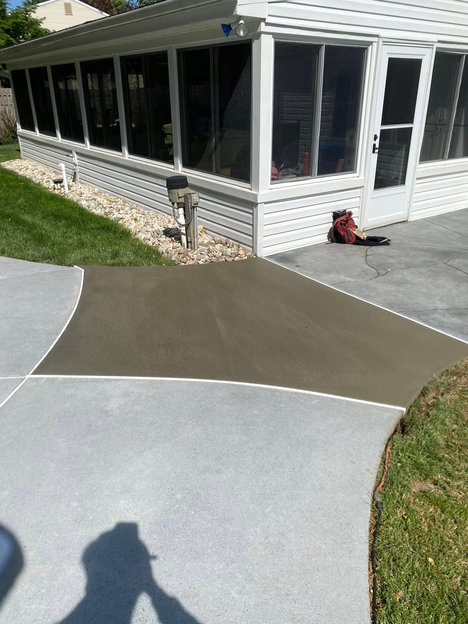 Stamped concrete walkway beside a screened porch and white house exterior.