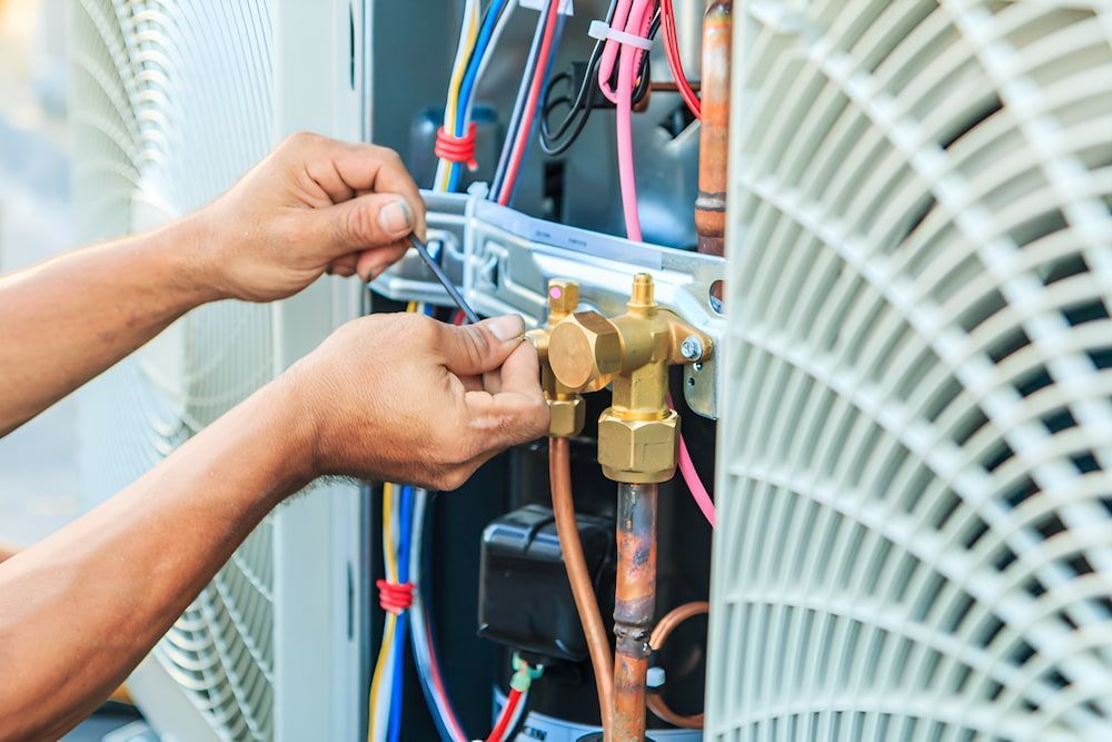 A Man Is Working On An Air Conditioner With A Wrench — Mason's Air Conditioning Pty Ltd in Drayton, QLD