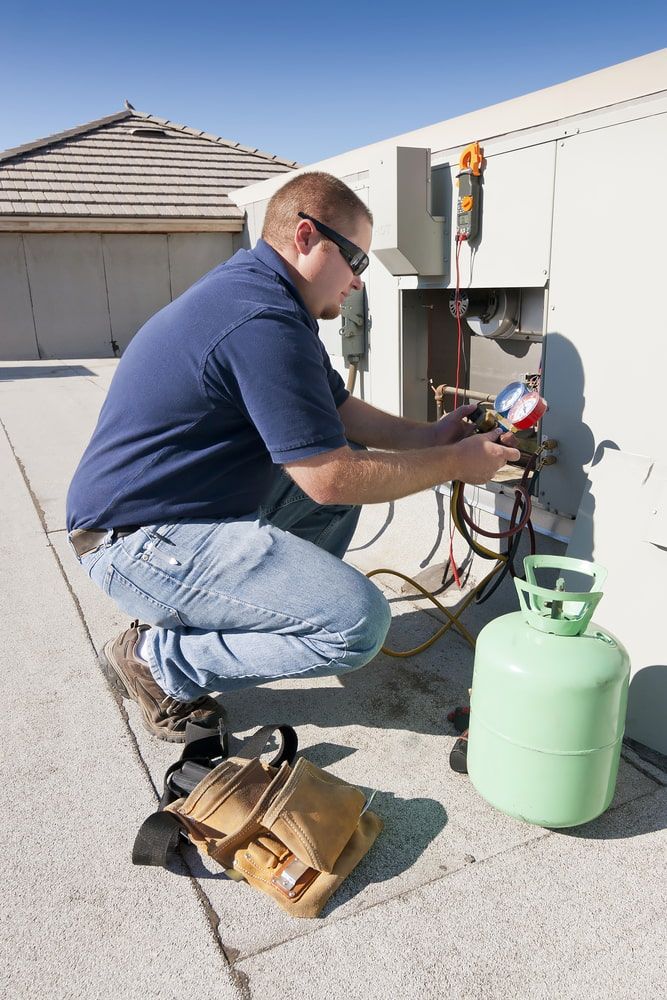 A Man Is Working On An Air Conditioner On The Roof — Mason's Air Conditioning Pty Ltd in Warwick, QLD
