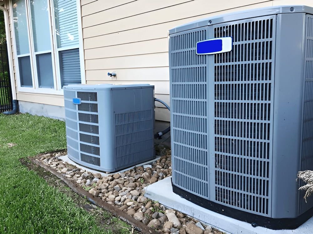 Two Air Conditioners Are Sitting On The Side Of A House — Mason's Air Conditioning Pty Ltd in Drayton, QLD