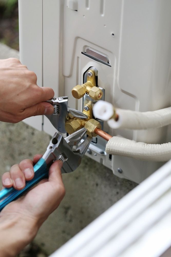 A Person Is Working On An Air Conditioner With A Wrench And Pliers — Mason's Air Conditioning Pty Ltd in Drayton, QLD