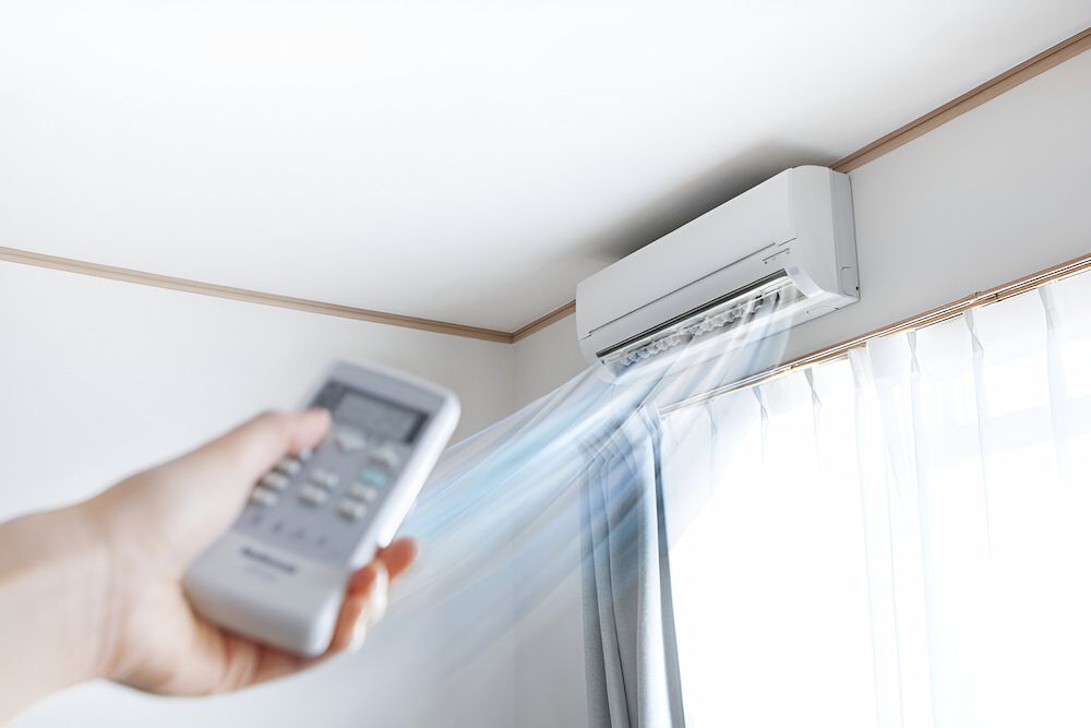 A Person Is Holding A Remote Control In Front Of An Air Conditioner — Mason's Air Conditioning Pty Ltd in Drayton, QLD