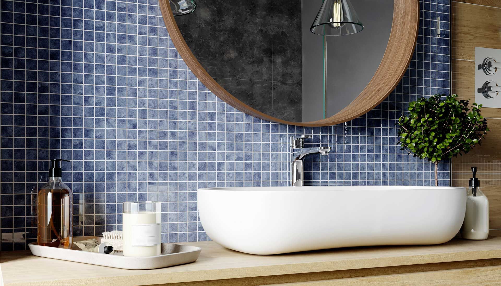Modern bathroom vanity with round mirror, white vessel sink, blue mosaic tiles, and a potted plant