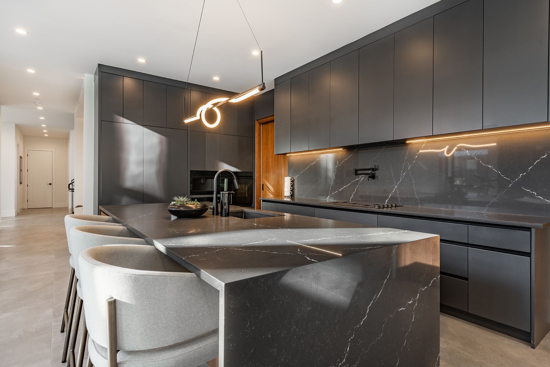 Modern black kitchen with marble island, dark cabinets, and pendant lighting