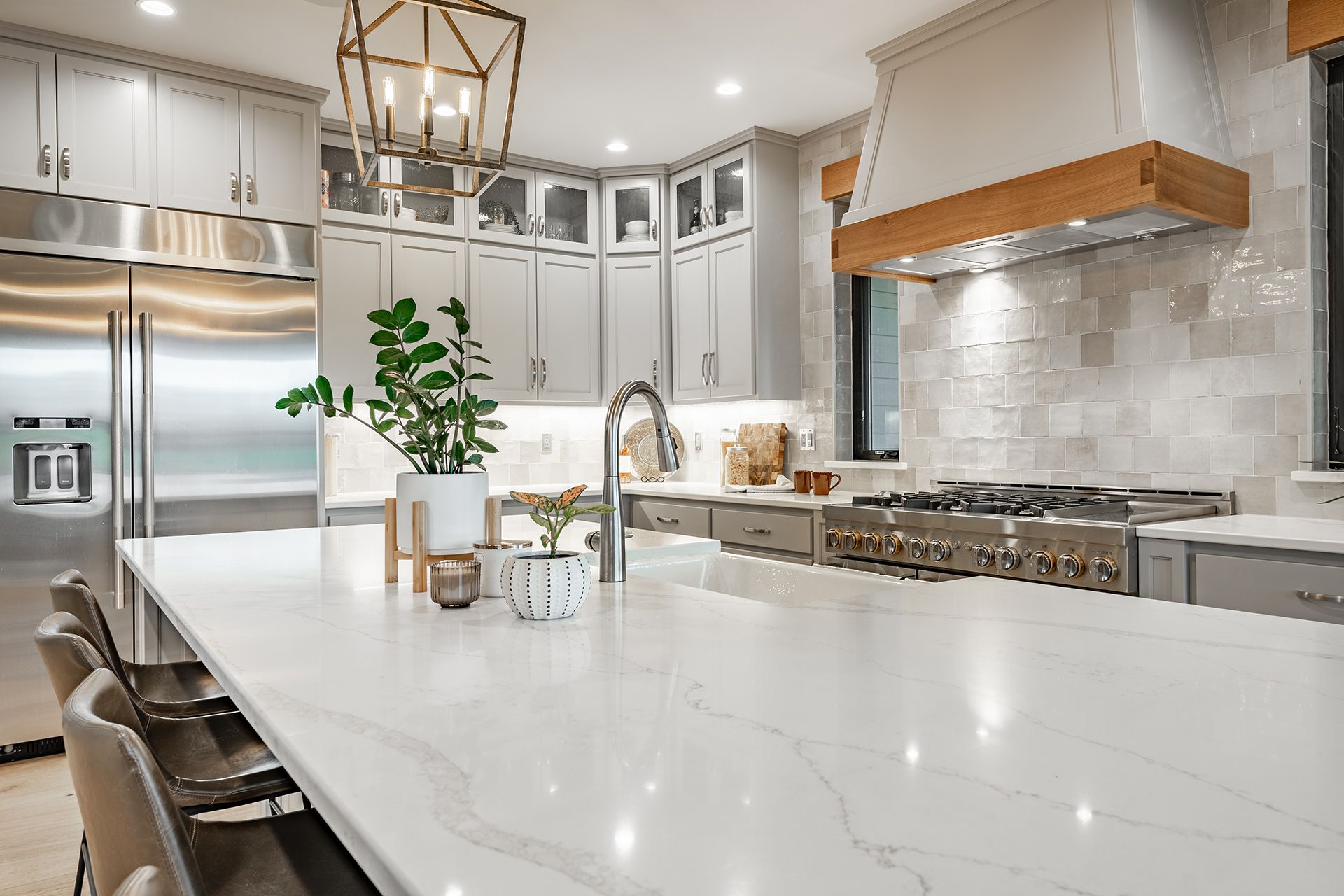 Bright modern kitchen with white island, stainless steel appliances, and marble backsplash