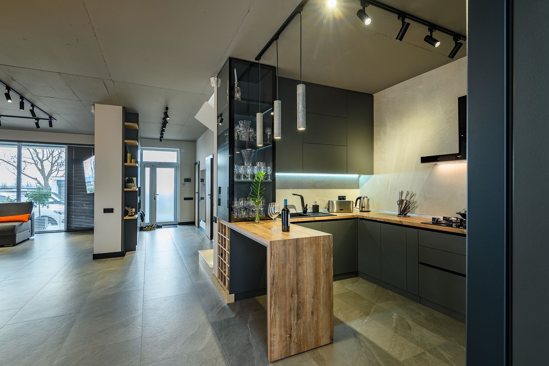 Modern open-plan kitchen with dark cabinets, wood island, and black track lighting