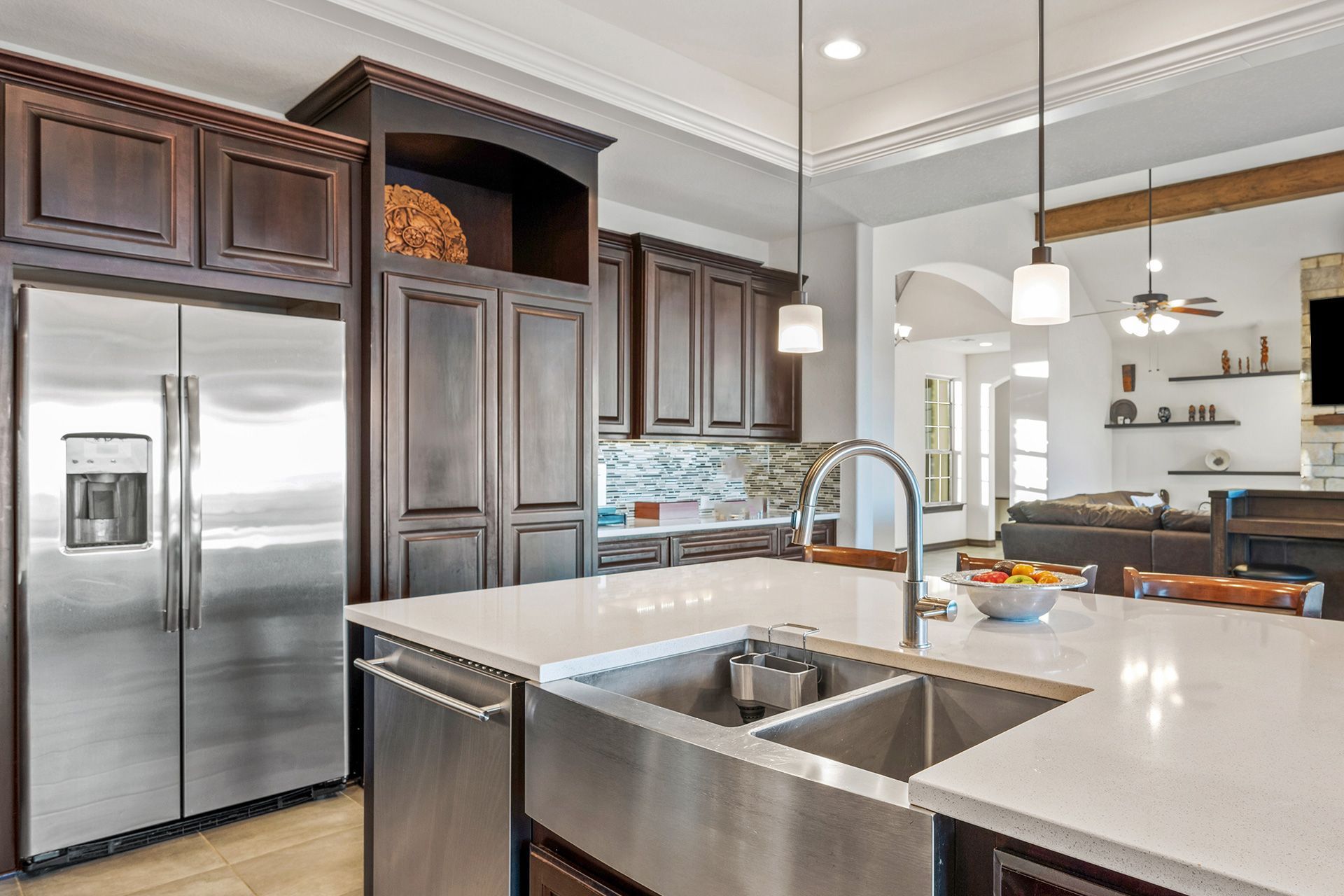 Modern kitchen with stainless steel appliances, dark cabinets, and a white island with sink.